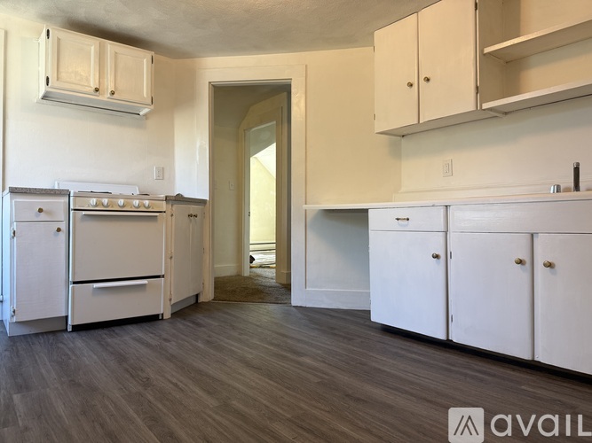 A kitchen with white cabinets and a wooden floor.
