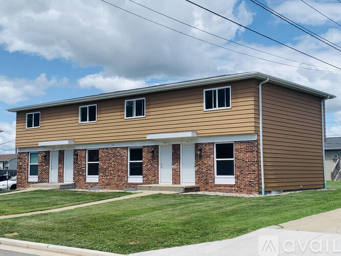 A two-story house with a brown siding and a brick base.
