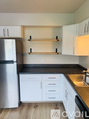 A kitchen with white cabinets and a stainless steel refrigerator.