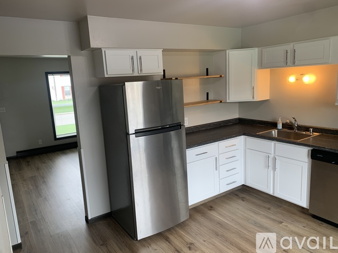 A kitchen with a stainless steel refrigerator and white cabinets.