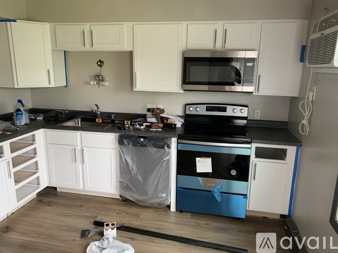 A kitchen with white cabinets and a black countertop.
