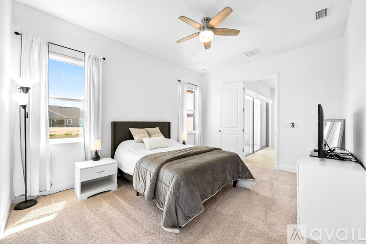 A bedroom with a large bed and a ceiling fan.