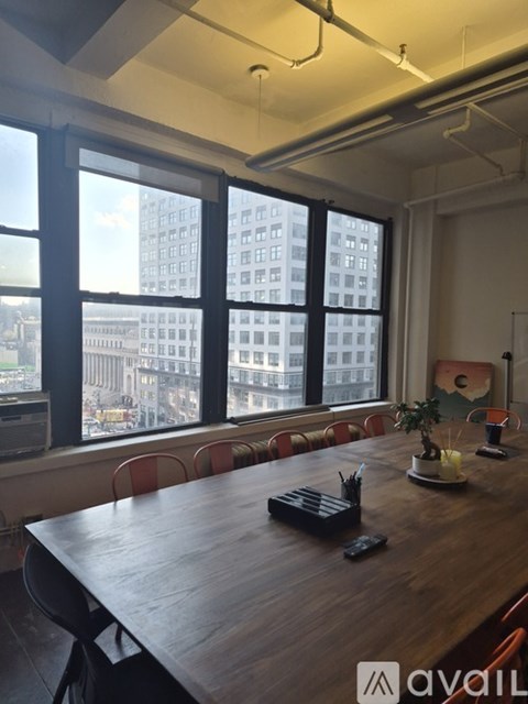 A conference room with a long table and chairs, a potted plant, and a view of a cityscape through large windows.