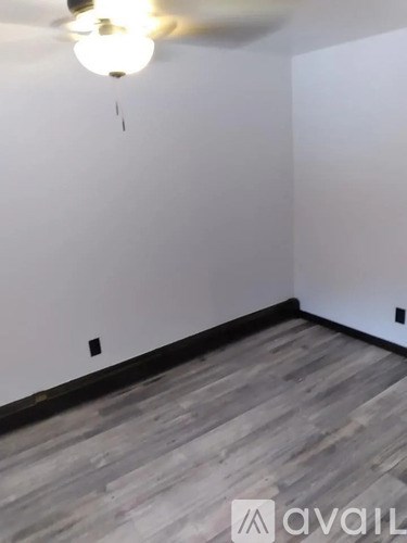 A room with a ceiling fan and wooden flooring.