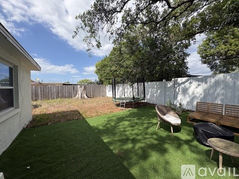 A backyard with a wooden fence, a green lawn, and a wooden bench.