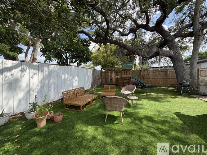 A backyard with a wooden bench, a chair, and a tree.