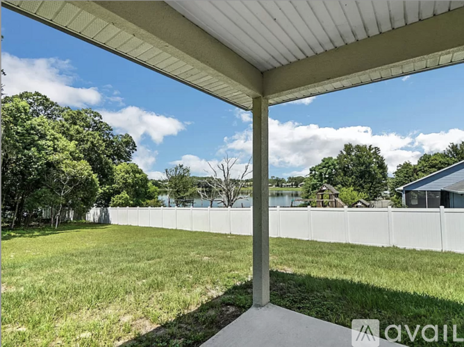 A covered outdoor area with a white fence and green grass.