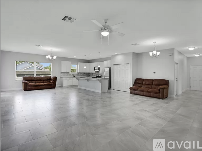 A spacious living room with a brown couch and a fan.