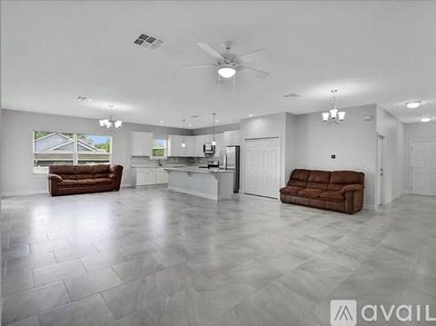 A spacious living room with a brown couch and a fan.