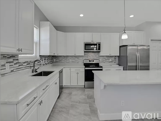 A modern kitchen with white cabinets and a marble countertop.