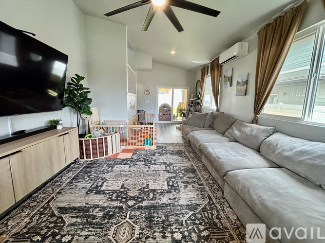 A living room with a large rug and a long white sofa.