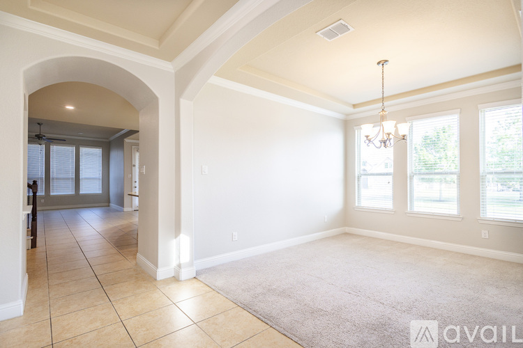 A spacious room with a chandelier and a rug on the floor.