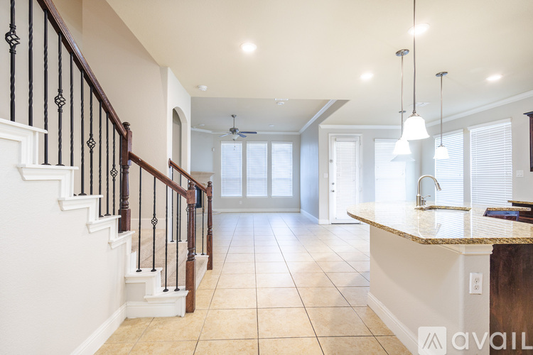 A spacious kitchen and living room with a staircase on the left.