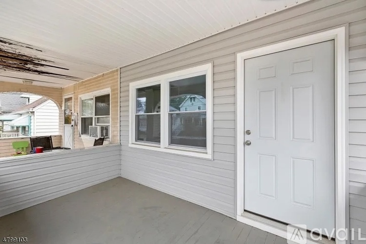 A white door is on the right side of a room with a window and a balcony.