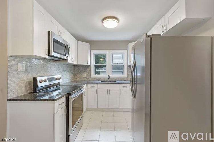 A kitchen with white cabinets and a black countertop.