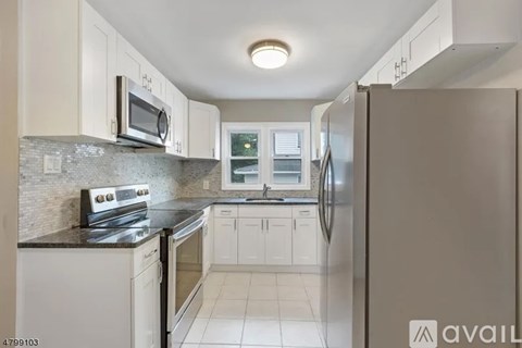 A kitchen with white cabinets and a black countertop.