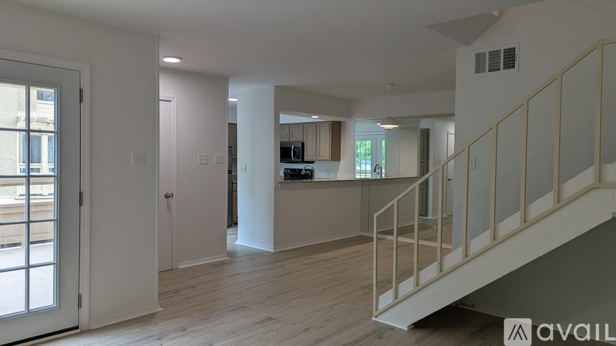 A spacious interior of a building with a staircase on the right and a window on the left.
