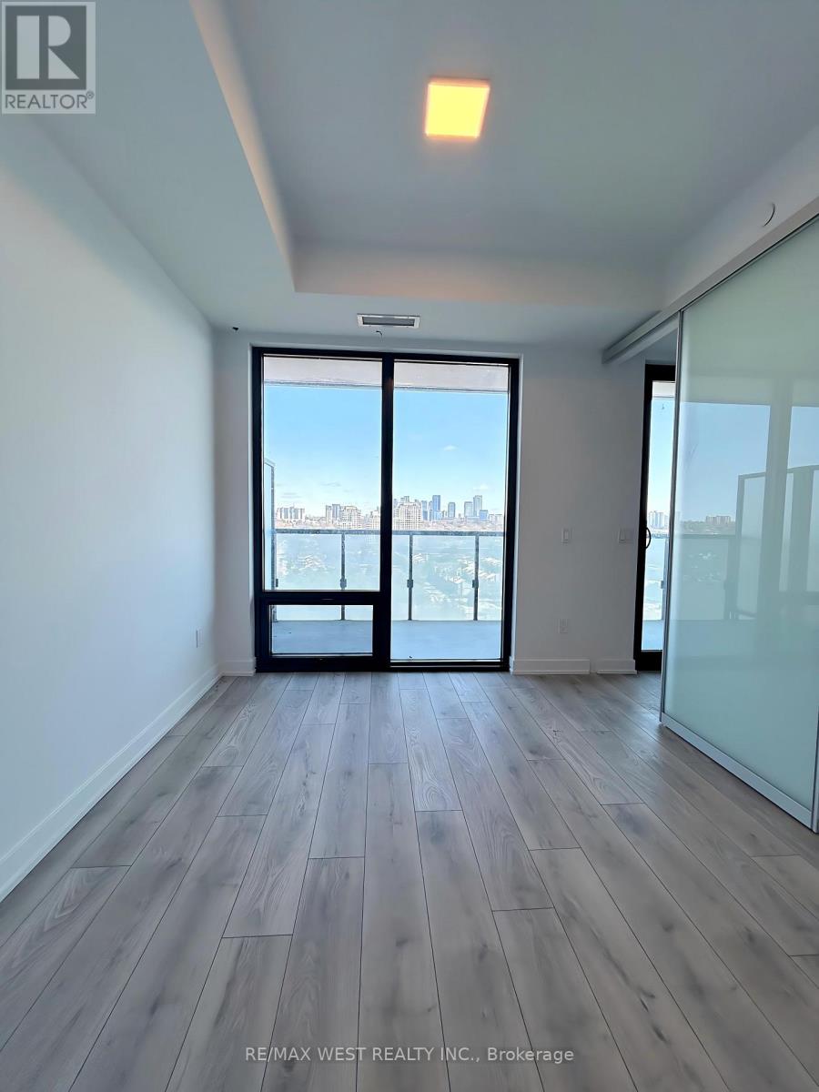 A spacious room with wooden flooring and a view of the city through a large window.