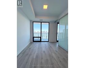 A spacious room with wooden flooring and a view of the city through a large window.