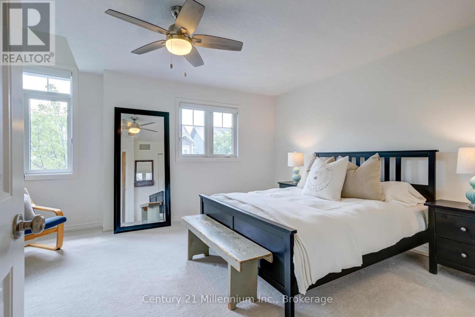 A bedroom with a bed, bench, and a fan.