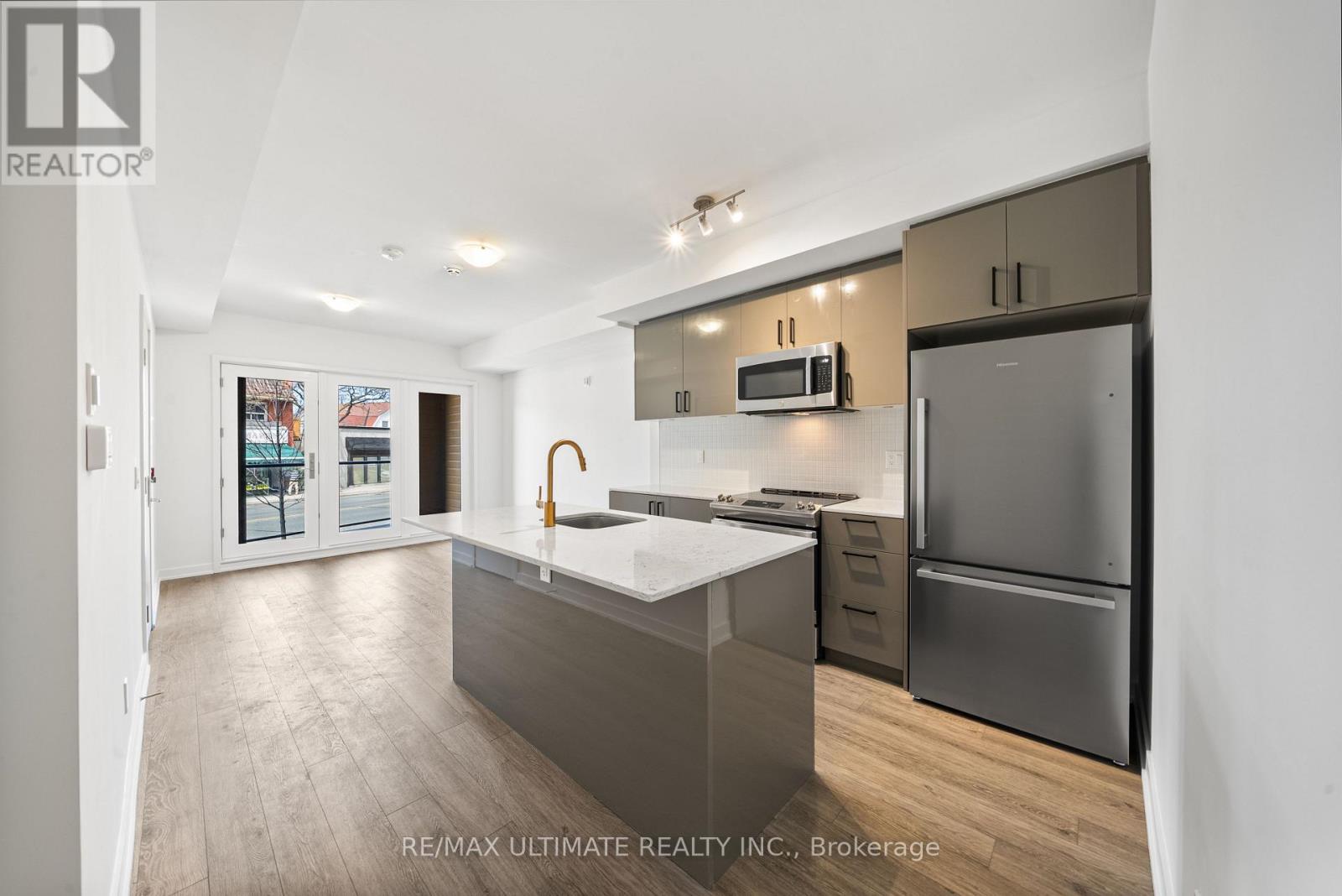 A modern kitchen with a refrigerator, microwave, and oven.