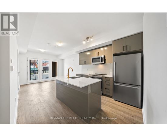 A modern kitchen with a refrigerator, microwave, and oven.