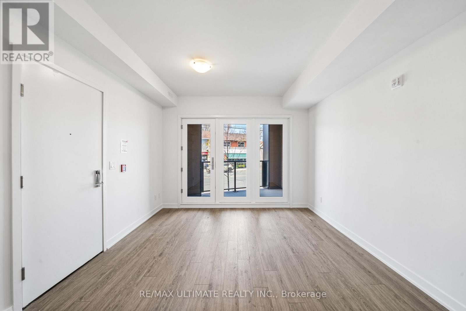 A white room with a wooden floor and a door leading to a balcony.