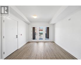 A white room with a wooden floor and a door leading to a balcony.