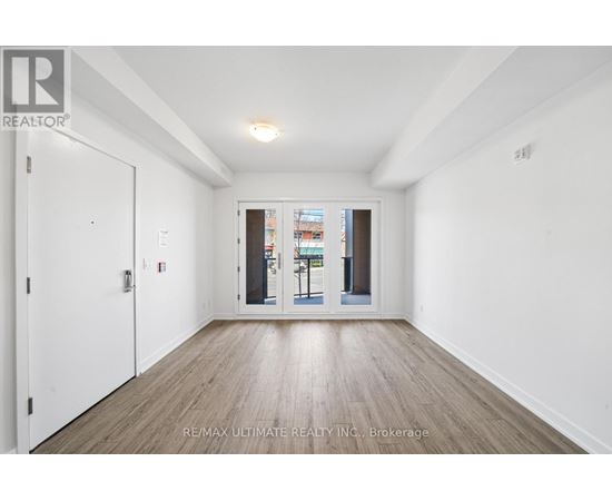 A white room with a wooden floor and a door leading to a balcony.