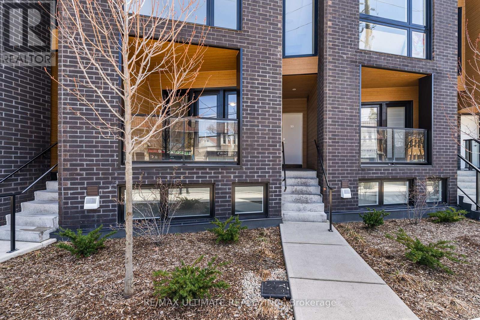 A modern brick building with a tree in front.