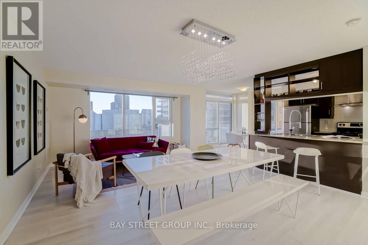 A modern living room with a dining table and chairs, a sofa, and a kitchen area in the background.