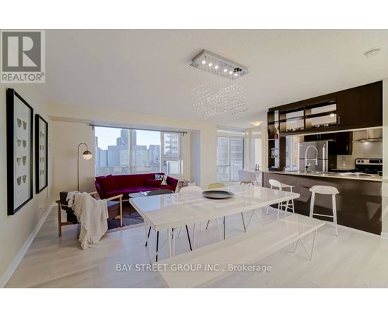 A modern living room with a dining table and chairs, a sofa, and a kitchen area in the background.