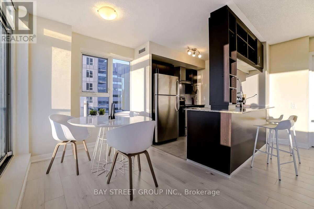 A modern kitchen with white chairs and a black counter.
