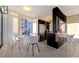 A modern kitchen with white chairs and a black counter.