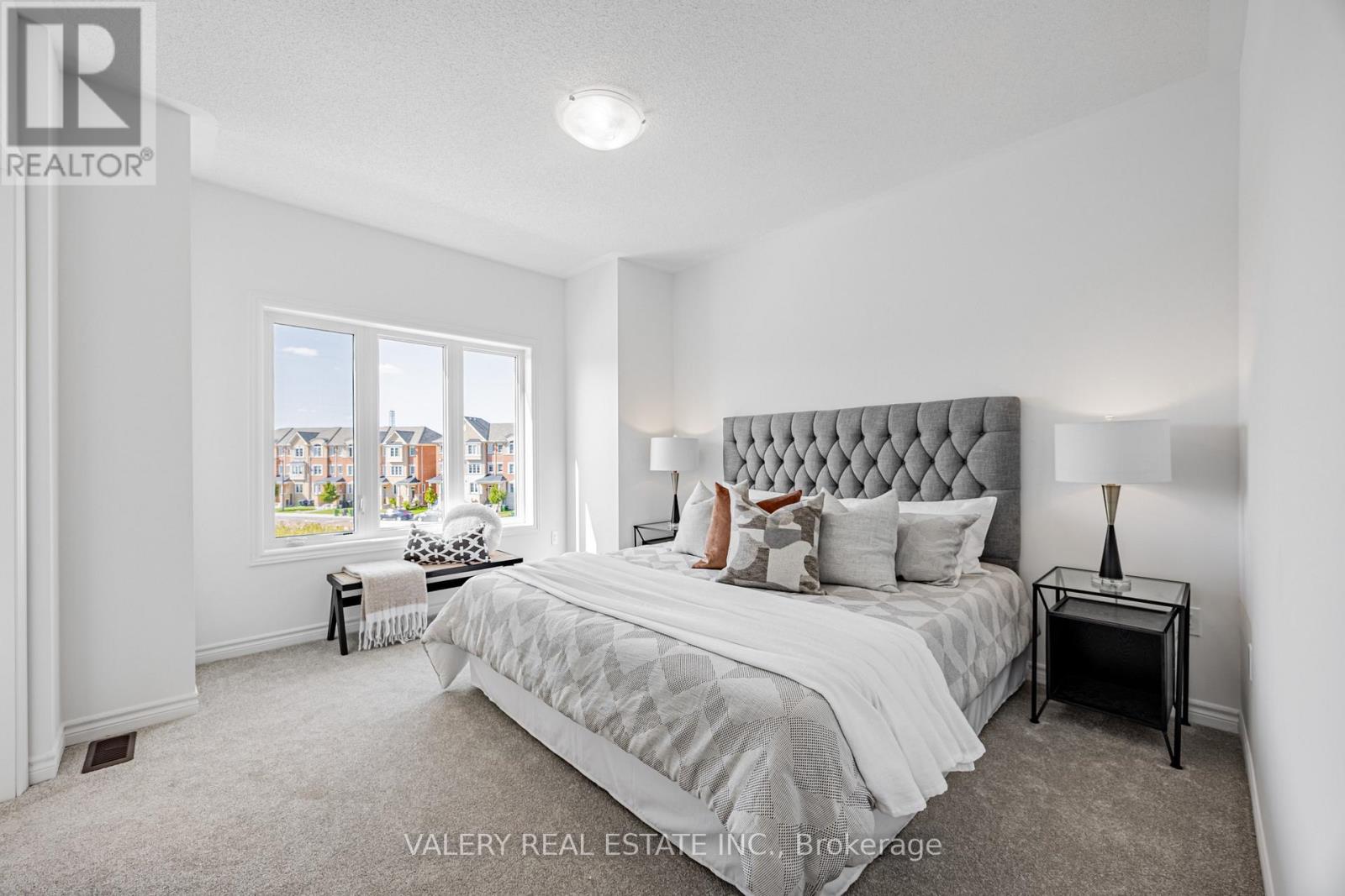A bedroom with a large bed, a nightstand, and a window overlooking a cityscape.
