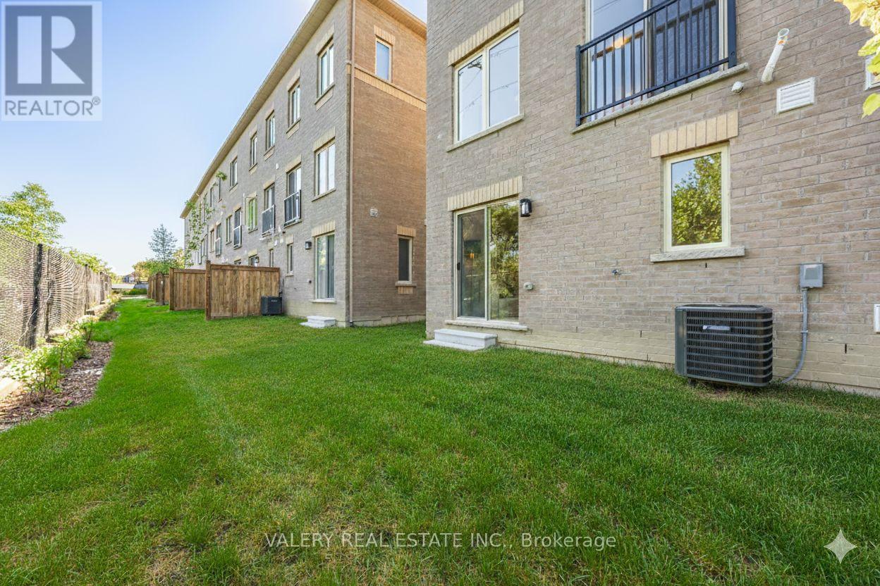 A grassy yard in front of a brick building with a sign that says Valery Real Estate Inc. Brokerage.