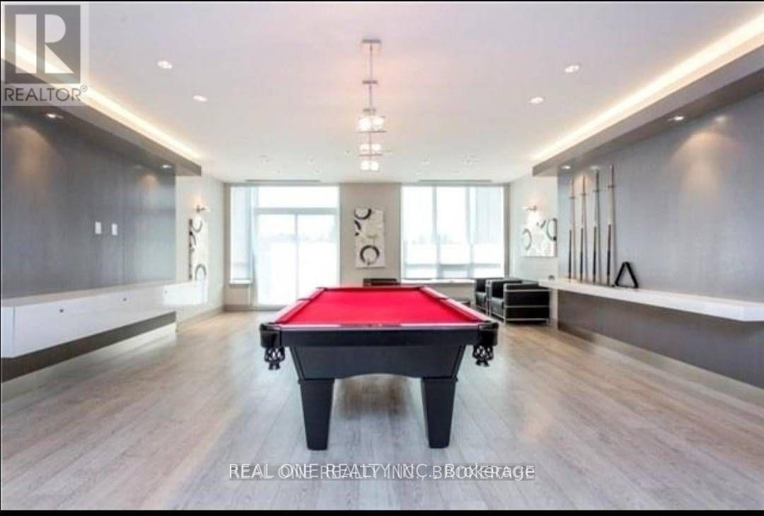 A pool table is in the middle of a room with a wooden floor and a wall with a window.