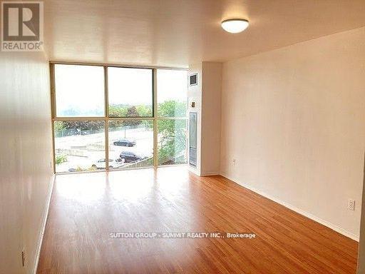 A room with a wooden floor and a large window overlooking a parking lot.