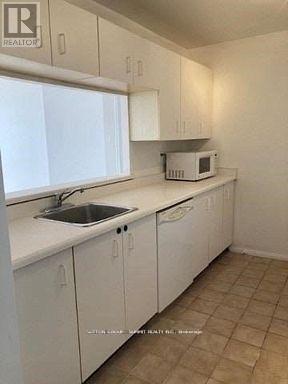 A kitchen with white cabinets and a microwave on the counter.