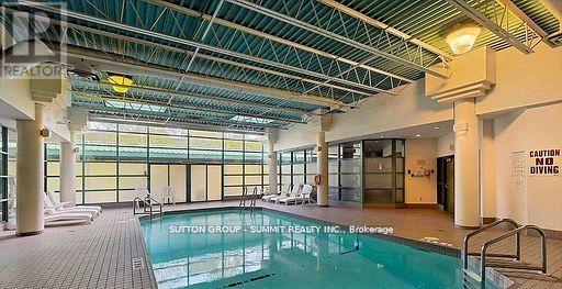 A large indoor swimming pool with a caution sign for diving.