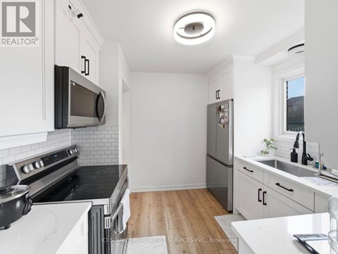 A modern kitchen with white cabinets and a wooden floor.