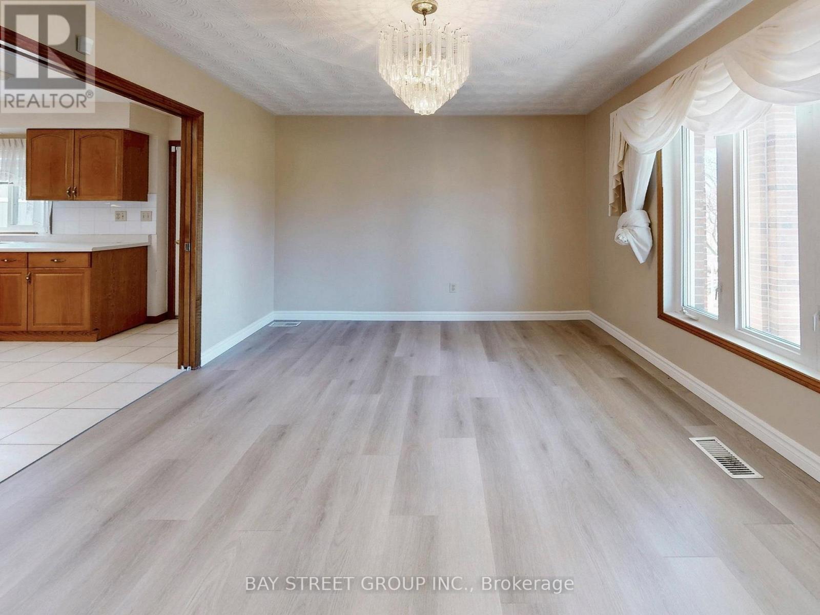 A spacious room with wooden flooring and a chandelier.