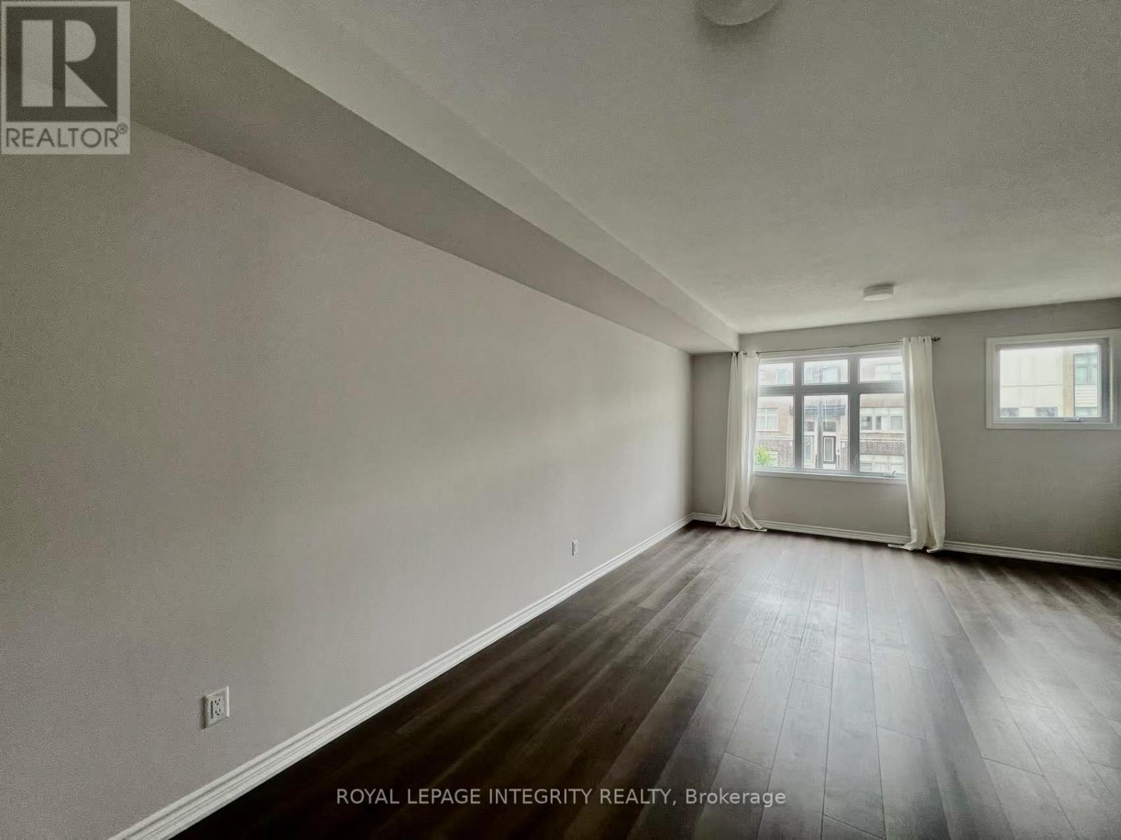 A spacious room with wooden flooring and white walls.
