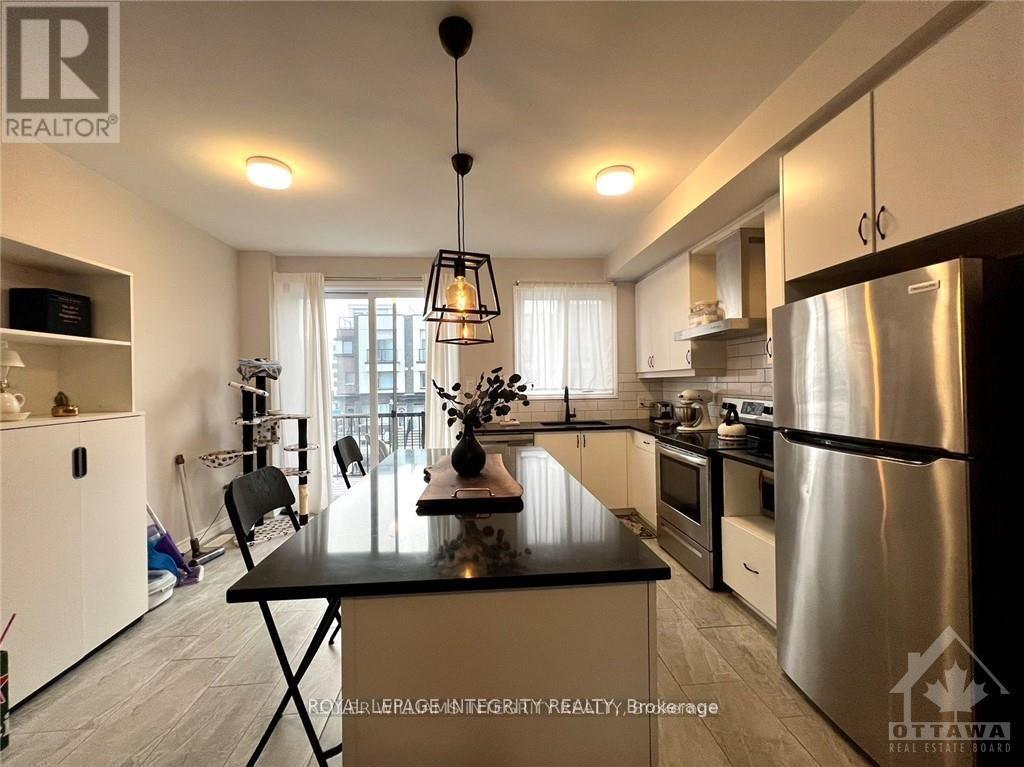 A modern kitchen with a black countertop and stainless steel appliances.