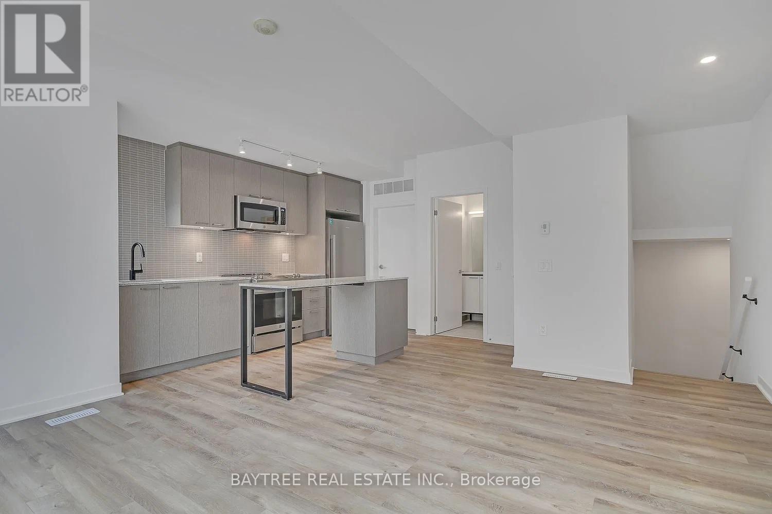 A spacious, well-lit kitchen with wooden flooring and white walls.