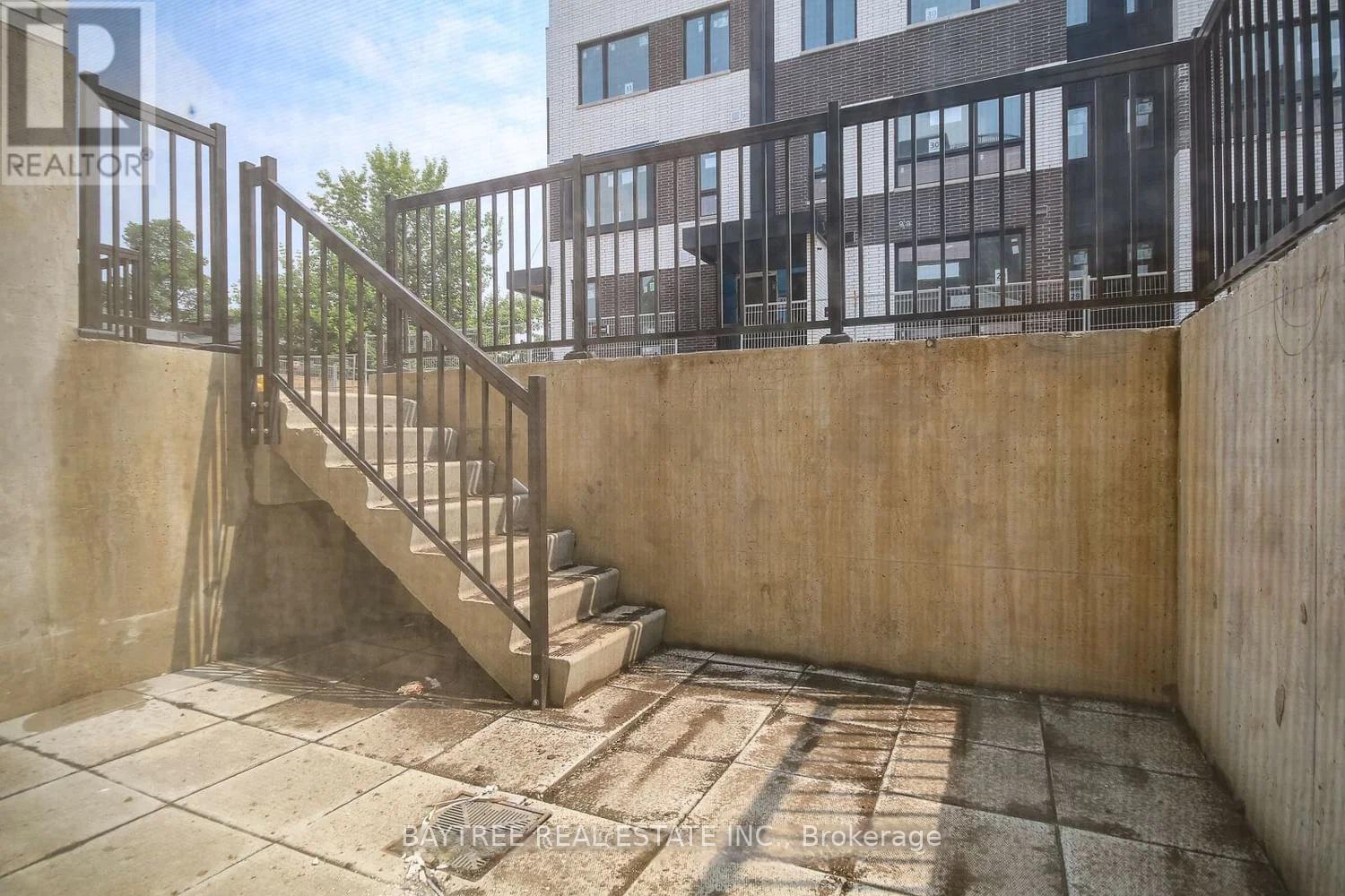 A concrete staircase with a metal railing leads up to a building.