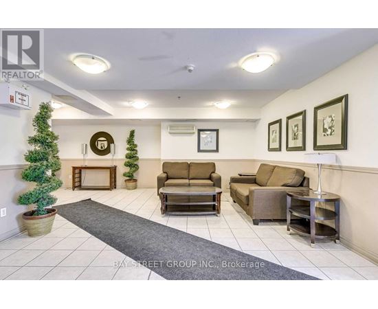 A living room with a couch, chair, and a small tree in a pot.
