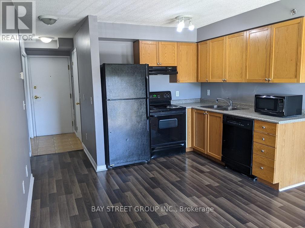 A kitchen with wooden cabinets and a black refrigerator.
