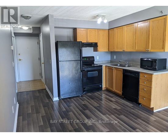 A kitchen with wooden cabinets and a black refrigerator.