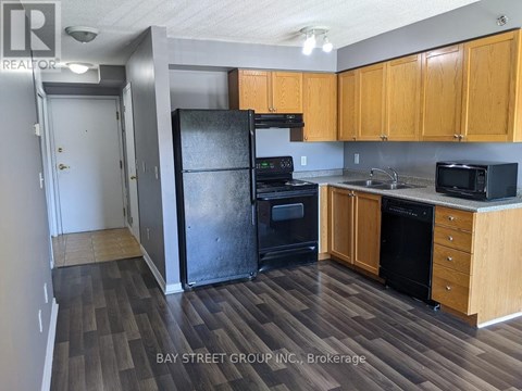 A kitchen with wooden cabinets and a black refrigerator.
